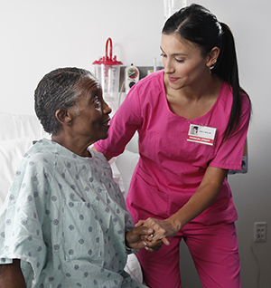 Healthcare provider helping woman out of hospital bed.