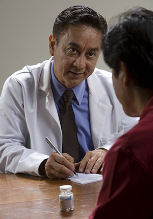 Man talking to doctor with pill bottle on table.