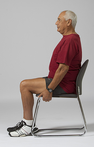 Man sitting in chair, holding the seat