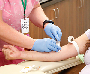 Healthcare provider drawing blood from woman's arm.