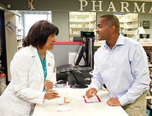 Farmacéutico hablando con un hombre en el mostrador de la farmacia.