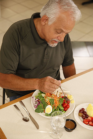 Hombre comiendo una ensalada.